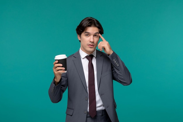 Uomo d'affari elegante carino bell'uomo in abito da ufficio grigio e cravatta pensando e tenendo una tazza di caffè