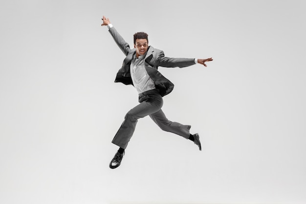 Uomo d'affari felice ballando in movimento isolato su sfondo bianco studio. Flessibilità e grazia negli affari. Concetto di emozioni umane. Ufficio, successo, professionale, felicità, concetti di espressione
