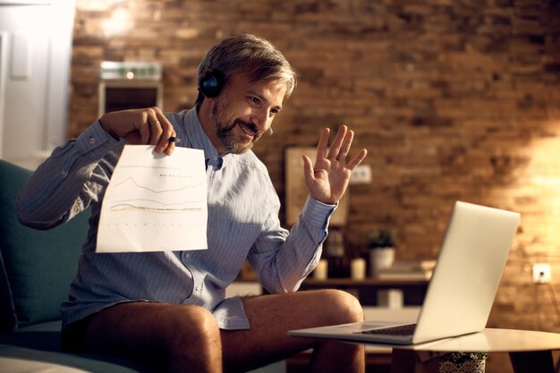 Uomo d'affari felice che ha una chiamata in conferenza sul laptop da casa