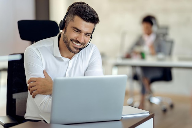 Uomo d'affari felice che lavora su un computer in ufficio