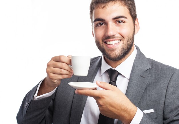 Uomo d&#39;affari felice che propone con una tazza e un piattino