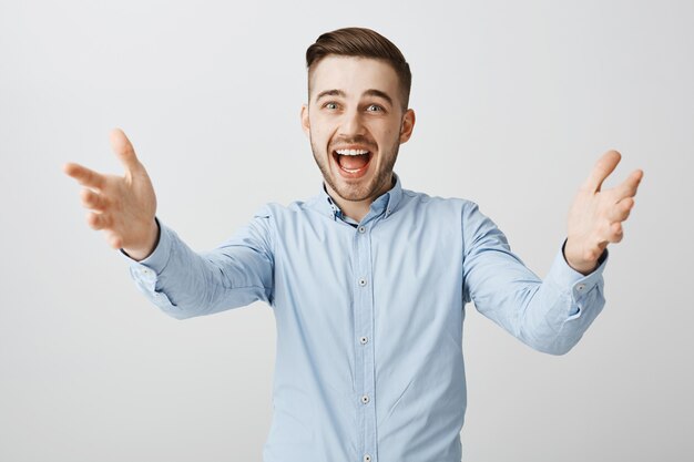 Uomo d'affari felice eccitato che raggiunge le mani per salutare qualcuno, prendendo premio, tenendo il prodotto