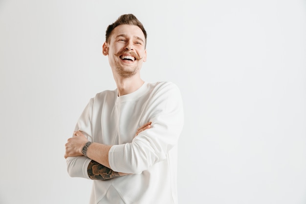 Uomo d'affari felice in piedi, sorridente isolato su sfondo grigio studio. Bellissimo ritratto maschile a mezzo busto. I giovani soddisfano l'uomo. Emozioni umane, concetto di espressione facciale.