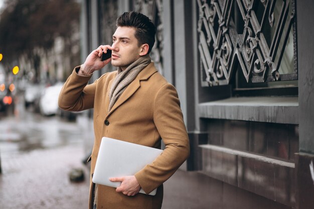 Uomo d&#39;affari in cappotto con il portatile fuori