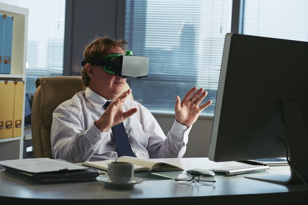 Uomo d'affari in cuffia avricolare di VR nel suo ufficio