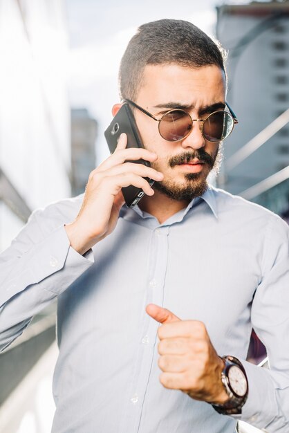 Uomo d&#39;affari in occhiali da sole con il telefono