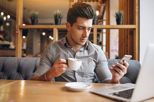 Uomo d&#39;affari in un caffè a parlare al telefono e bere caffè