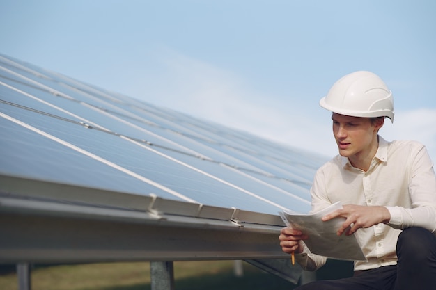 Uomo d'affari in un casco bianco vicino alla batteria solare