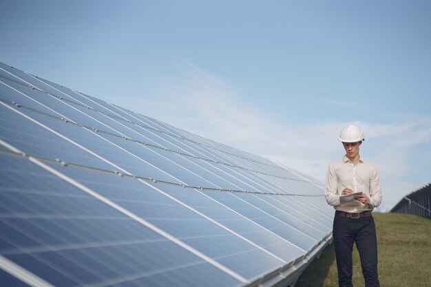 Uomo d'affari in un casco bianco vicino alla batteria solare