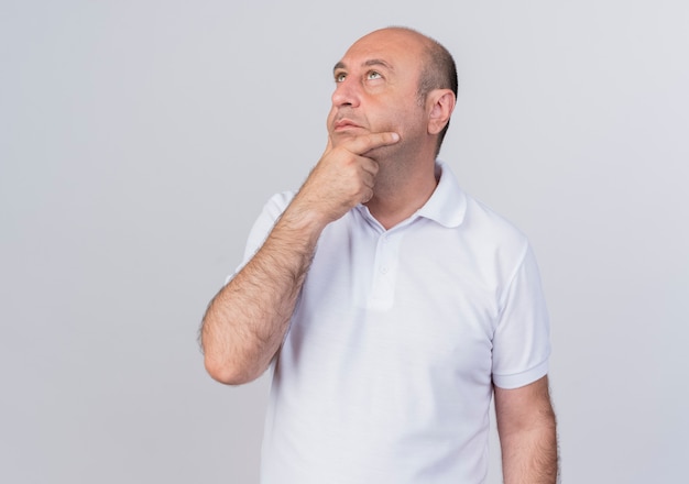 Uomo d'affari maturo casuale premuroso che mette la mano sul mento e che osserva in su isolato su fondo bianco con lo spazio della copia