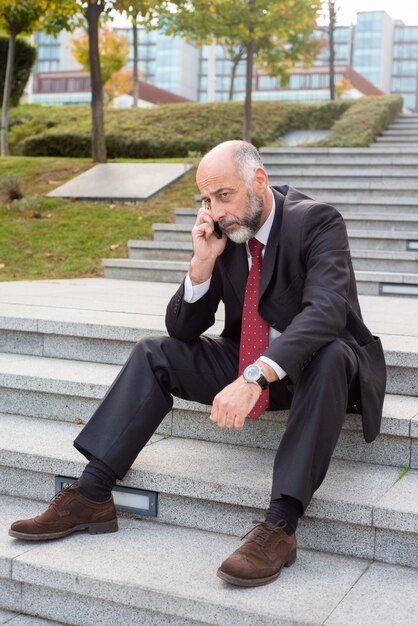 Uomo d'affari maturo stanco che parla sul cellulare