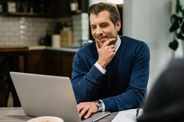 Uomo d'affari metà adulto sorridente che legge un'e-mail mentre lavora al computer