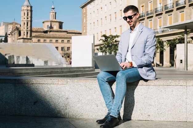 Uomo d&#39;affari moderno che per mezzo del computer portatile all&#39;aperto