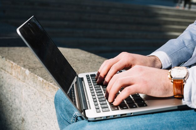 Uomo d&#39;affari moderno che per mezzo del computer portatile all&#39;aperto