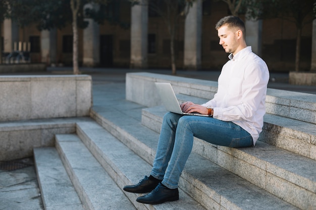 Uomo d&#39;affari moderno che per mezzo del computer portatile all&#39;aperto