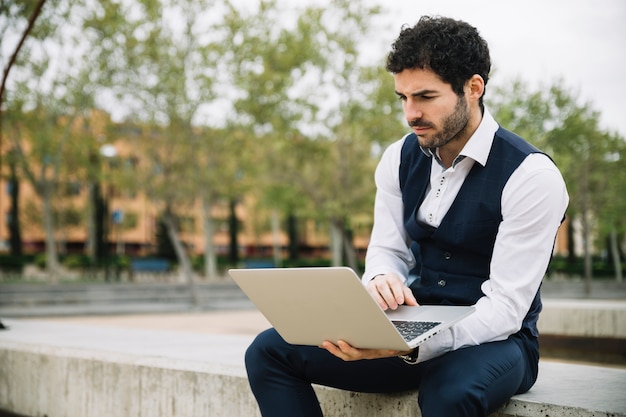 Uomo d&#39;affari moderno che per mezzo del computer portatile all&#39;aperto