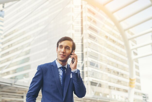 Uomo d&#39;affari parlando sul telefono cellulare contro l&#39;edificio all&#39;aperto.