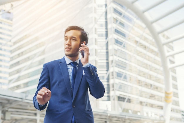 Uomo d&#39;affari parlando sul telefono cellulare contro l&#39;edificio all&#39;aperto.