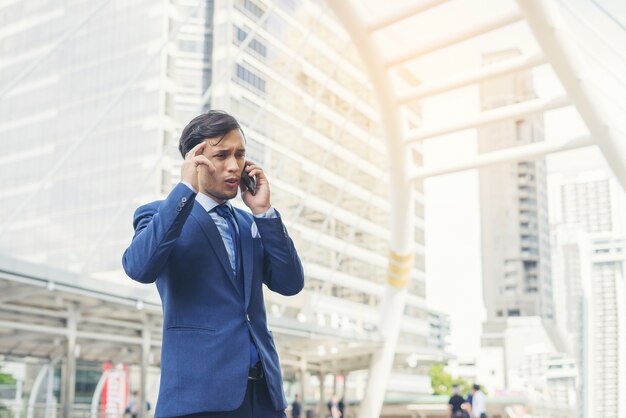 Uomo d&#39;affari parlando sul telefono cellulare contro l&#39;edificio all&#39;aperto.