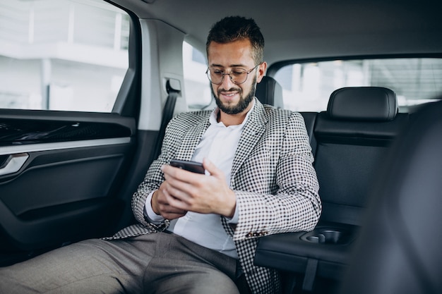 Uomo d'affari seduto sul sedile posteriore di un'auto utilizzando tablet