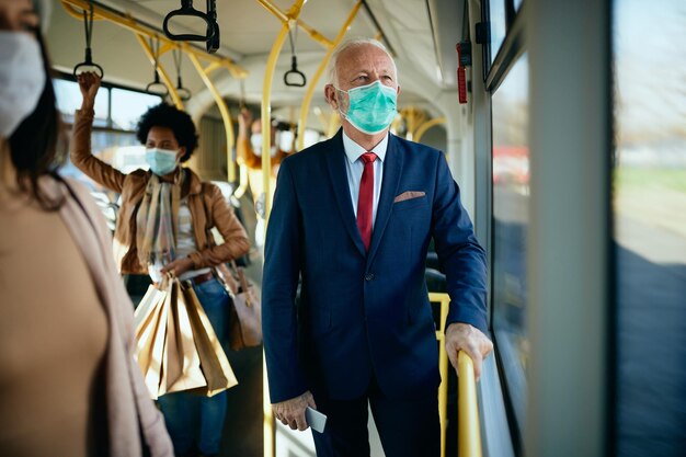 Uomo d'affari senior che indossa una maschera protettiva in un trasporto pubblico