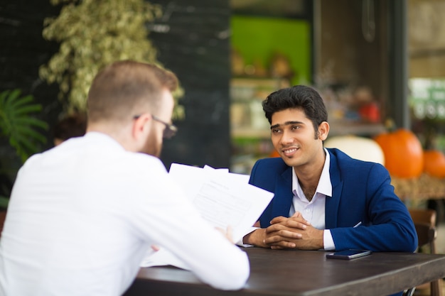 Uomo d&#39;affari sorridente che aspetta quando contratto della lettura del partner