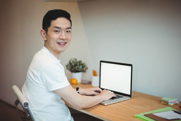 Uomo d'affari sorridente che lavora al computer portatile
