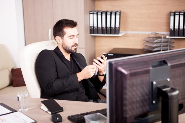 Uomo d'affari sorridente che parla al telefono mentre lavora nel suo ufficio. Imprenditore in ambiente professionale