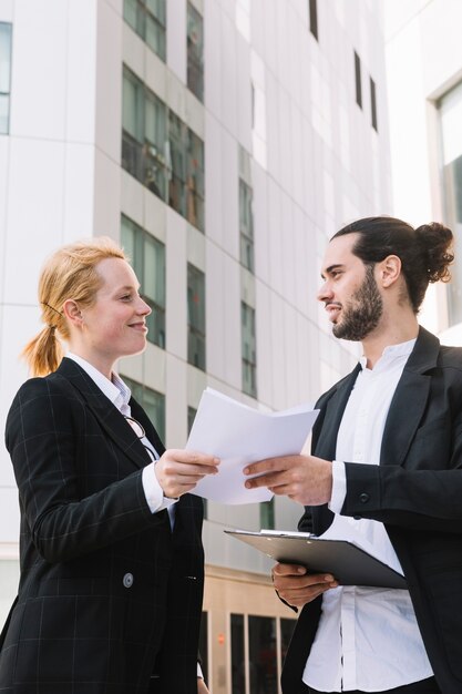 Uomo d&#39;affari sorridente e lavoro di ufficio della tenuta della donna di affari in mani a all&#39;aperto