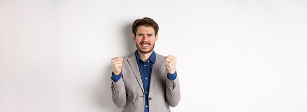 Uomo d'affari teso che si sente nervoso e sotto pressione stringendo pugni e denti fissando la macchina fotografica