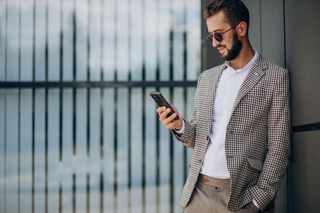 Uomo d'affari utilizzando il telefono al di fuori del centro ufficio