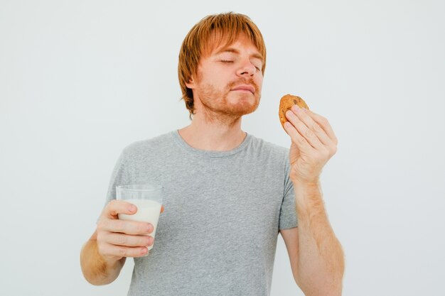 Uomo dai capelli rossi con un bicchiere di latte che puzzava il biscotto