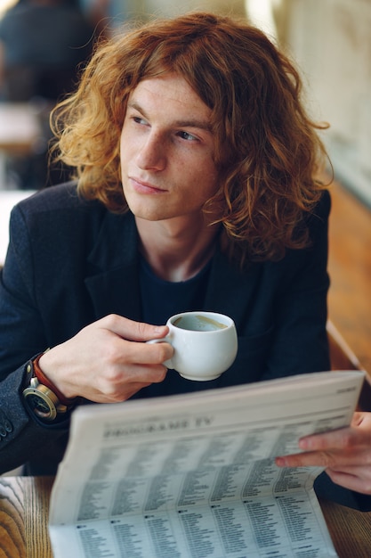 Uomo dei pantaloni a vita bassa che beve caffè mentre pensando al futuro