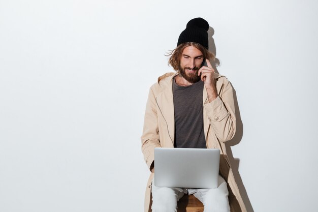 Uomo dei pantaloni a vita bassa che guarda da parte con il computer portatile