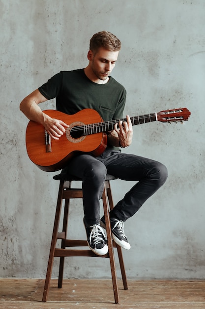 Uomo del chitarrista che gioca chitarra a casa