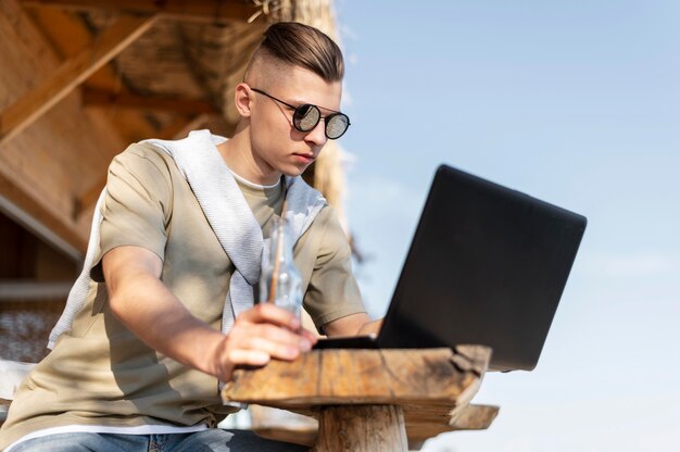 Uomo del colpo medio all'aperto con il computer portatile