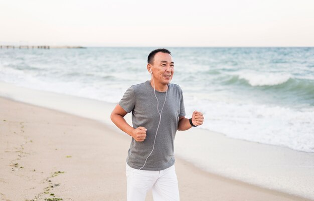 Uomo del colpo medio che corre sulla spiaggia