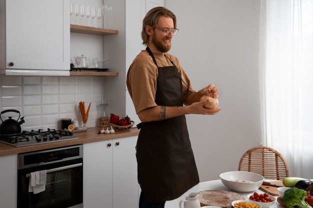 Uomo del colpo medio che cucina pizza