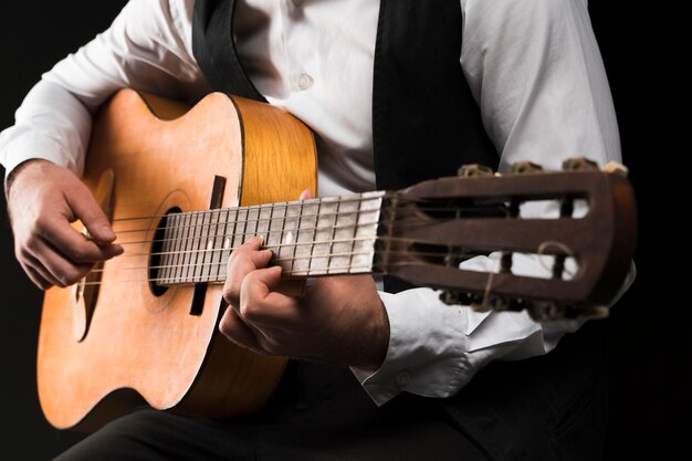 Uomo del colpo medio che gioca la chitarra classica