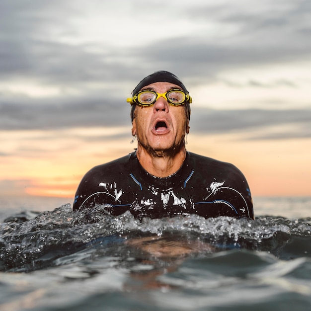 Uomo del colpo medio che nuota nel mare