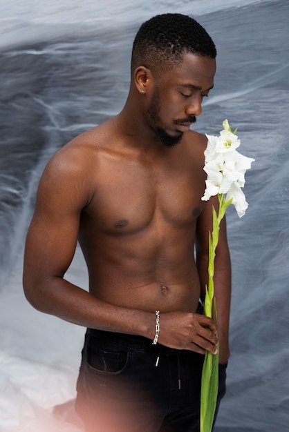 Uomo del colpo medio che posa con il fiore bianco