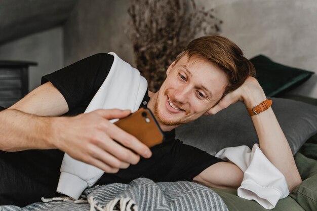 Uomo del colpo medio che sorride allo smartphone