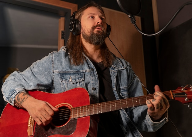 Uomo del colpo medio che suona la chitarra in studio