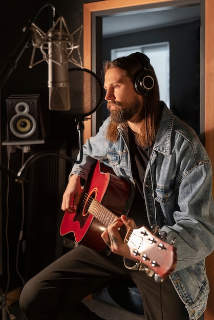 Uomo del colpo medio che suona la chitarra in studio