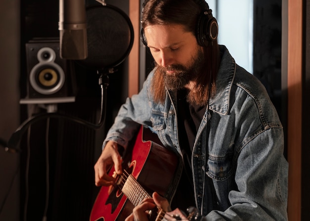 Uomo del colpo medio che suona la chitarra in studio