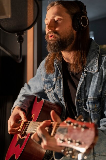 Uomo del colpo medio che suona la chitarra in studio