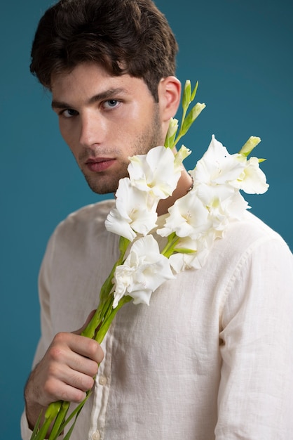 Uomo del colpo medio che tiene fiori bianchi