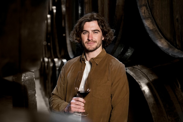 Uomo del colpo medio che tiene il bicchiere di vino