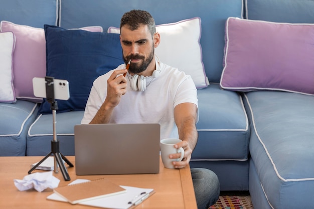 Uomo del colpo medio con il computer portatile a casa