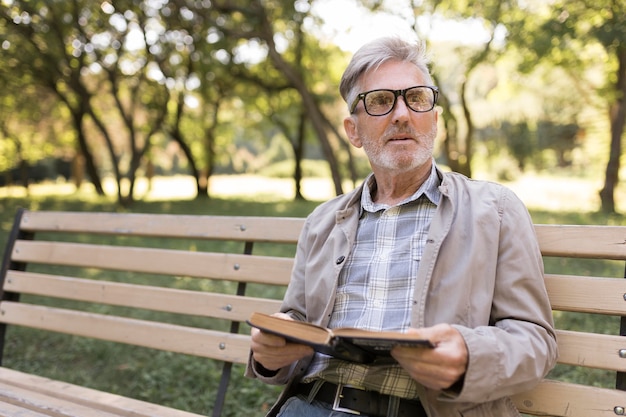 Uomo del colpo medio con il libro nel parco